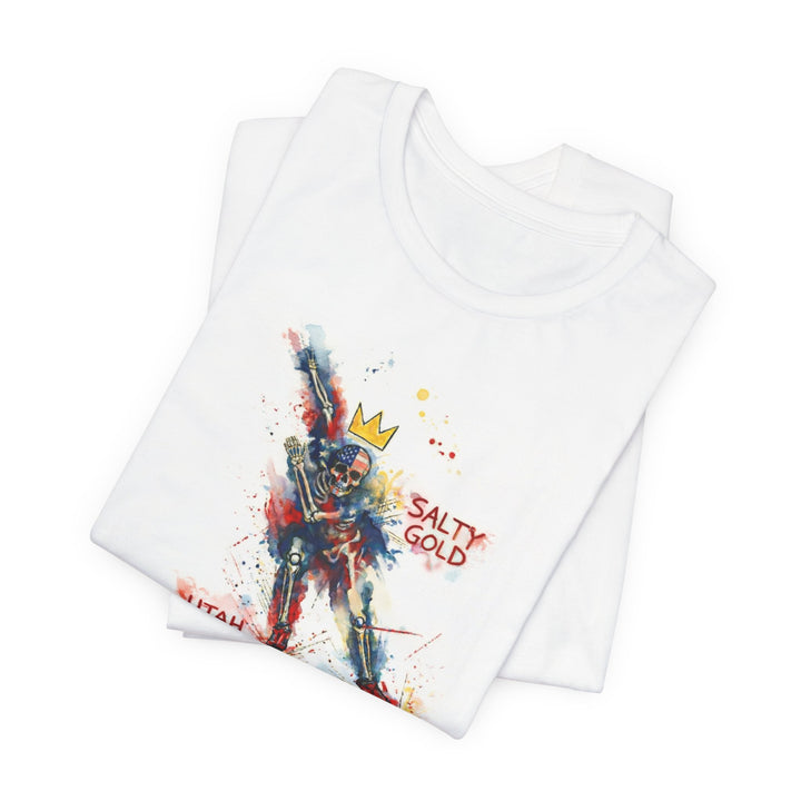 Salty Gold Long Track Skeleton Tee. White folded t-shirt with colorful watercolor skeleton, crown, and American flag design.