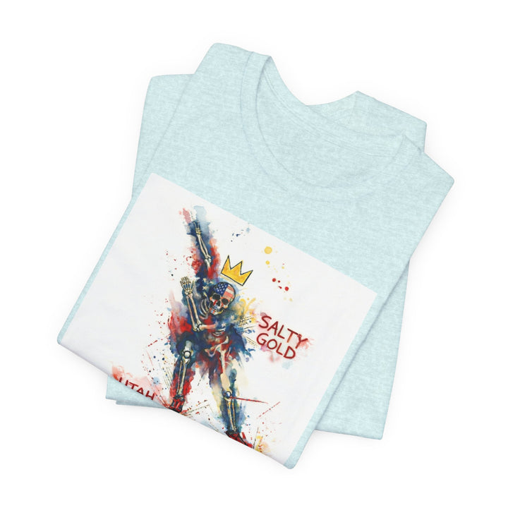 Salty Gold Long Track Skeleton Tee. Folded light blue t-shirt with red, blue, gold watercolor skeleton design.