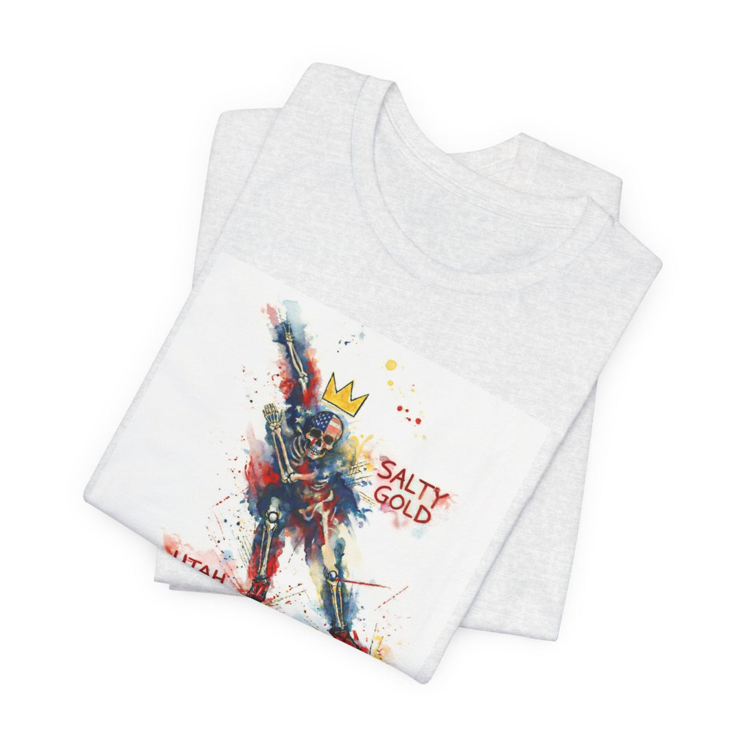 Folded white Salty Gold Long Track Skeleton Tee with watercolor skeleton design, red, blue, gold crown.